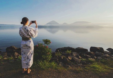 beautiful japanese girl use smart phone taking photo lake toya view, toyako, hokkaido,japan at the morning, use filter
