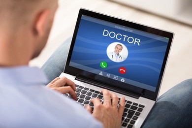 close-up of a man using laptop to communicate with doctor