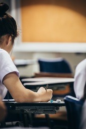soft focus.high school or university student holding pencil writing on paper answer sheet.sitting on lecture chair taking final exam attending in examination room or classroom.student in uniform.