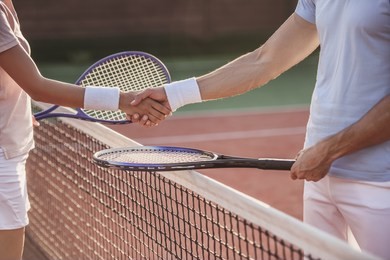 cropped image of man and woman shaking their hands while playing tennis on tennis court outdoors