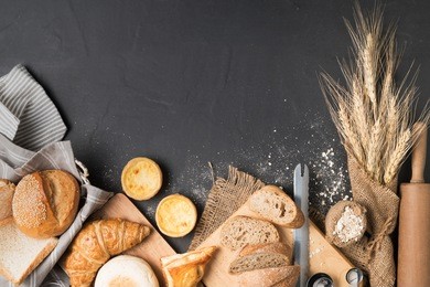 bakery concept: bread, croissant, baguette, muffin and egg tart on black stone background