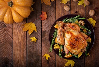 roasted turkey garnished with cranberries on a rustic style table decorated with pumpkins, orange, apples and autumn leaf. thanksgiving day. flat lay. top view