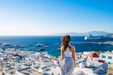 girl in white dress  looking at mykonos town, greece