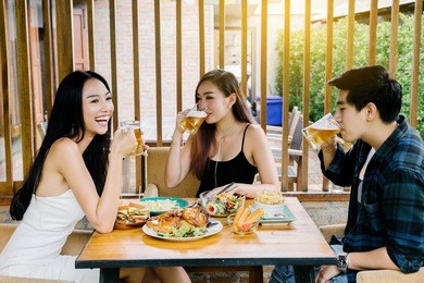 group of young asian people sitting at table in restaurant and having fun while dining.