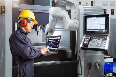 maintenance engineer using laptop computer control automatic robotic hand with cnc machine in smart factory, industry 4.0 concept