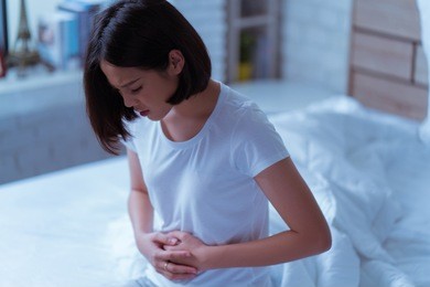 asian women her stomach aches hard she wakes up in the middle of the night while she sleeps.