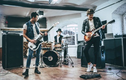 repetition of rock music band. bass guitar player, electric guitar player and drummer behind the drum set. rehearsal base