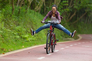 young woman cyclist fun riding bike on forest trail