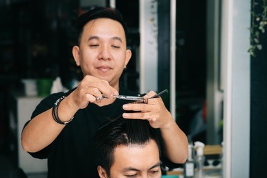 barber doing fashionable haircut for young man