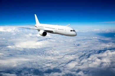 white passenger plane in flight. aircraft flies high in the blue sky over clouds.
