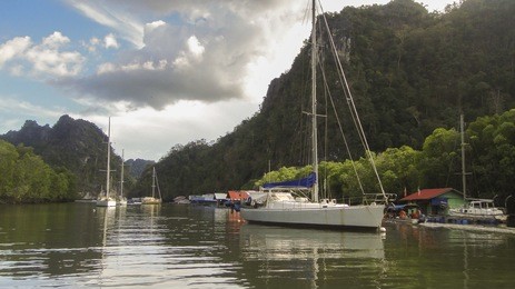 beautiful view of landscape and waterscape with yachts parking around kilim geo-forest nature park with cloudy blue sky, langkawi kedah malaysia. some soft focus due to view from travelling boat. 