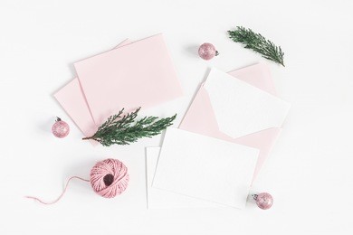 christmas composition. envelopes, christmas pink decorations, cypress branches on white background. top view, flat lay, copy space