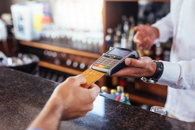 customer making payment using credit card. close up of card payment being made between customer and bartender in cafe.