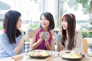 happy woman friends sitting and chatting in restaurant