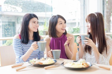 happy woman friends sitting and chatting in restaurant