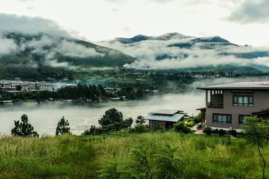 bhutanese village near the river on a foggy day at punakha, bhutan.