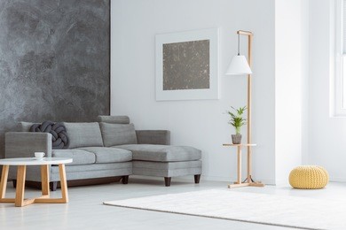 side angle of white minimalist living room with gray accents, painting, sofa, lamp, scandinavian coffee table and window