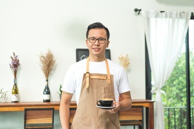 young asian man barista hold coffee cup at coffee shop counter background, start up small business owner food and drink concept.