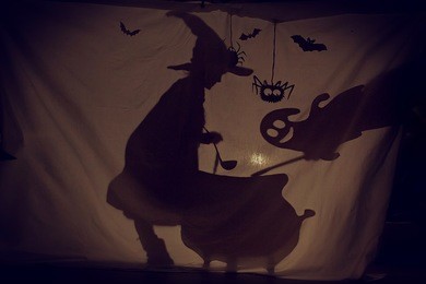 fabulous shadow the little witch at the cauldron brews a potion with a ghost.the theatre of shadows. . childhood. a magical story.halloween.