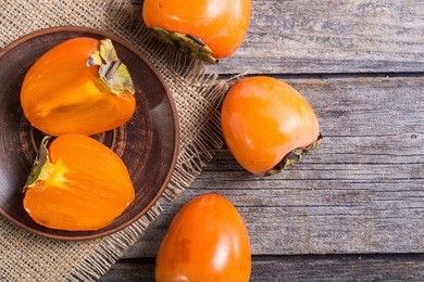 delicious ripe persimmon fruit on wooden background
