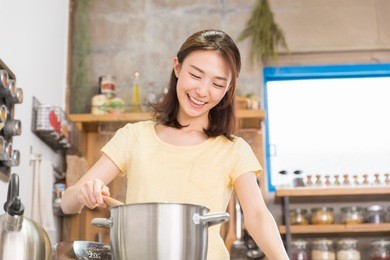 young attractive asian woman cooks in a kitchen