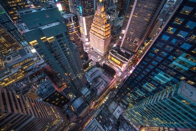 bird's eye view of manhattan, looking down at people and yellow taxi cabs going down 5th avenue. toned, instagram photography with slight vignette.