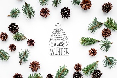 hello winter hand lettering with hat. winter pattern with spruce branch and cones on white background top view