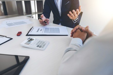 businessman will be signing a car insurance policy, agent man is holding the document and waiting for his reply to finish.
