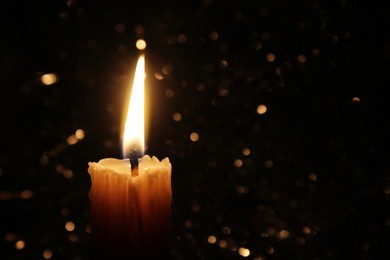 candles burning at night. white candles burning in the dark with focus on single candle in foreground. 