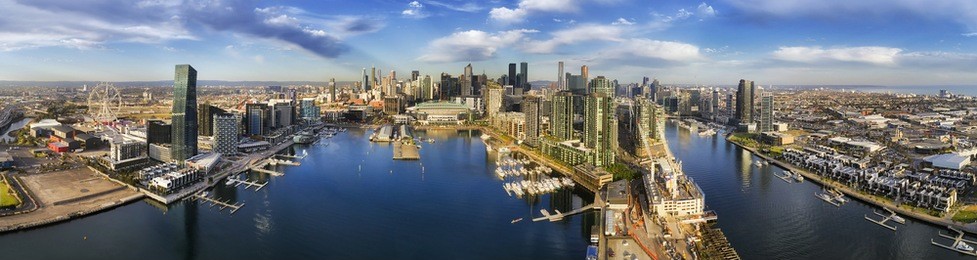 aerial wide panorama of melbourne docklands area over yarra river waters with marina yachts and wharfs. modern urban high-rise towers and architecture on cbd waterfront.