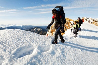 team of three alpinists climbing a mountain
