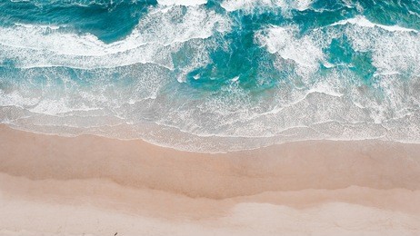 surfing aerial, beach on aerial drone top view with ocean waves reaching shore, top view aerial photo from flying drone of an amazingly beautiful sea landscape.