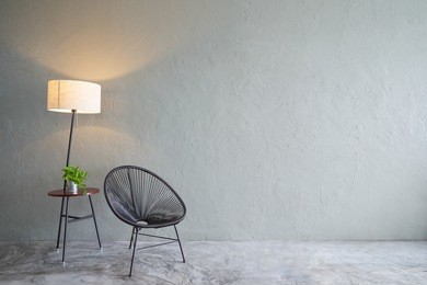 modern living room with black leisure chair ,green plant and lamp stand. cement floor and concrete wall , interior design with loft style .