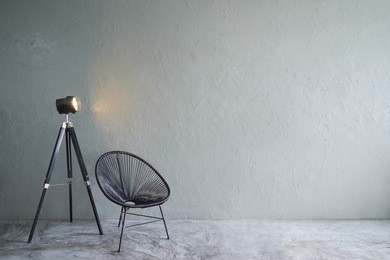 modern living room with black leisure chair ,green plant and lamp stand. cement floor and concrete wall , interior design with loft style .