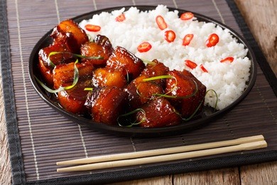 vietnamese spicy caramel pork belly with rice closeup on a plate on a table. horizontal