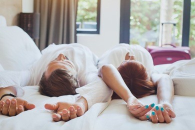 hotel guests relaxing on the bed in their room, couple traveling to luxurious resort