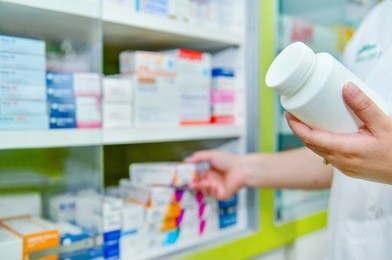 pharmacist holding bottle of medicine and capsule pack in pharmacy drugstore.