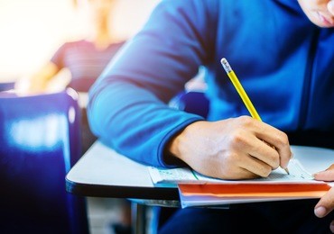 soft focus.high school or university student holding pencil writing on paper answer sheet.sitting on lecture chair taking final exam attending in examination room or classroom.
