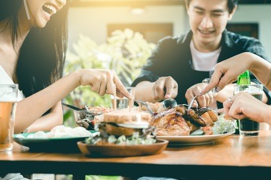 asian friends enjoying eating turkey at restaurant.