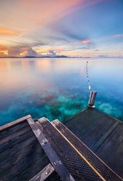 amazing hue of colorful mabul island sabah in sunset moment with crystal clear sea water and wooden jetty. motion of the clouds and wave are observed due to long exposure shot. nature composition