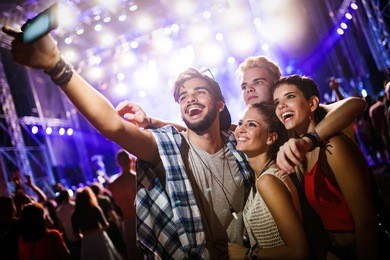 happy friends taking selfie at music festival