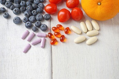 multivitamin supplements from fruit on white wooden background