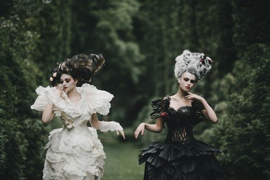 two women dresses like heroes from 'alice in wonderland' pose in a green park