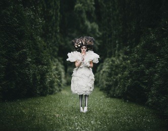woman dressed like a hero from 'alice in wonderland' poses in a green park