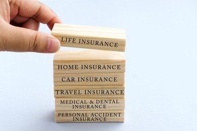 hand picking wood block with word life insurance. business concept type of insurances on wood top block with word: life, home, car, travel, medical and dental, personal accident. 