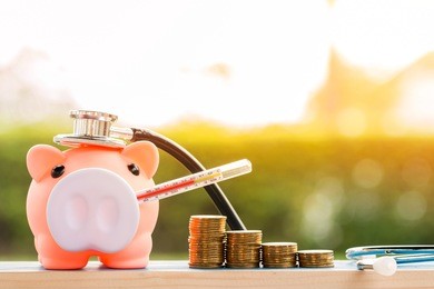 sick piggy bank use thermometer fever and stethoscope check hygiene and stack coin put on the wood on sunlight in the public park, saving money for buy health insurance concept.