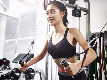 young asian woman working out in gym using exercising equipment.