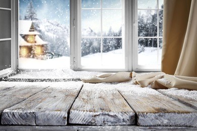 wooden table with space for your product. curtain in the window. open window with snowflakes. landscape of winter forest. morning sunshine.
