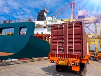 port operation loading container on board, the trucks pick up container to delivery for loading on container vessel.