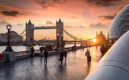 the tower bridge in london during sunrise and people rushing to their work